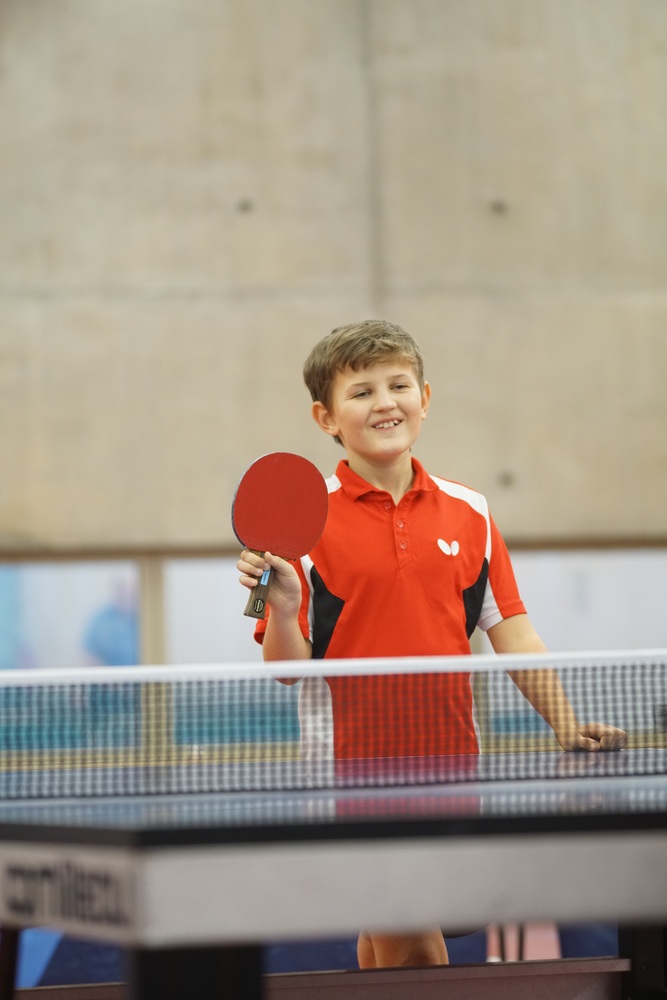 Jeune joueur de l'école de ping souriant